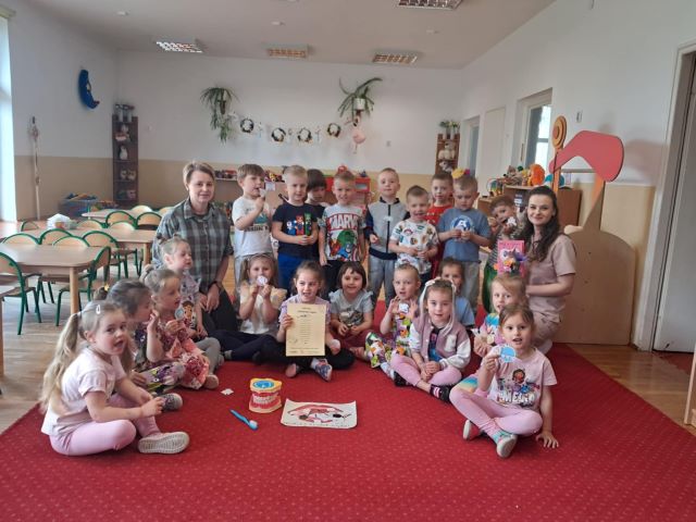 dzieci siedza na dywnie z asystentka dentysty