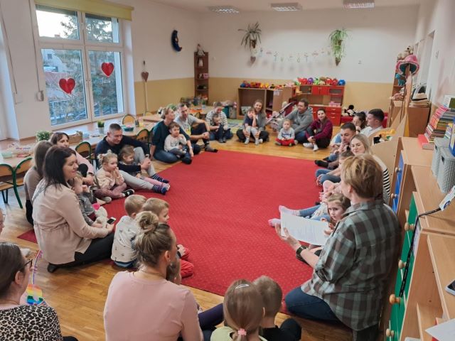 dzieci siedzą z rodzicami na dywanie