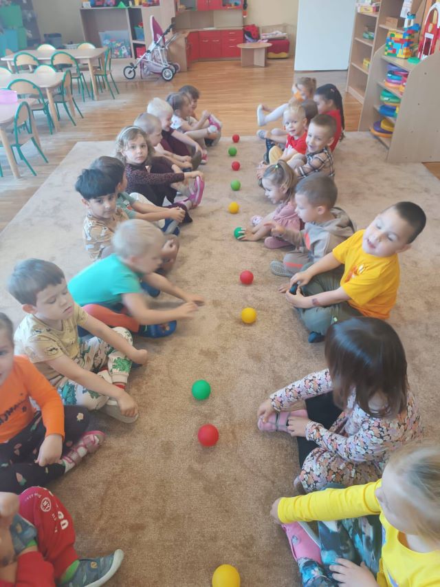 dzieci siedza na dywanie z piłeczkami