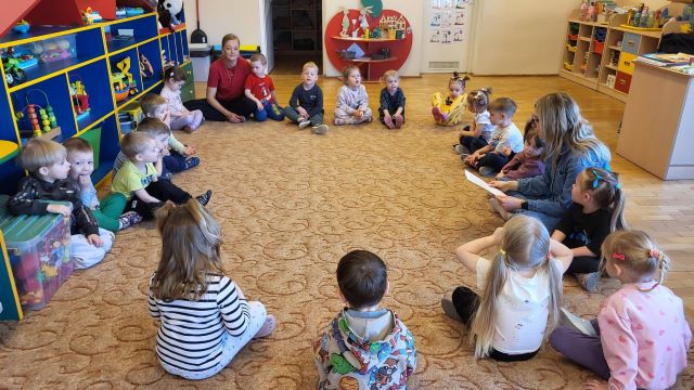 dzieci siedza na dywnie i sluchaja bajki